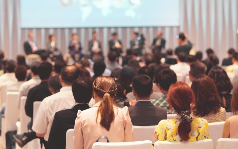 rear-view-of-audience-in-the-conference-hall-or-seminar-meeting-which-have-speakers-on-the-stage-e1700247411603